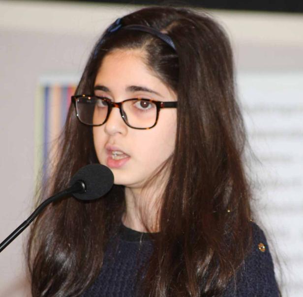 Ein junges Mädchen mit Brille spricht in ein Mikrofon.