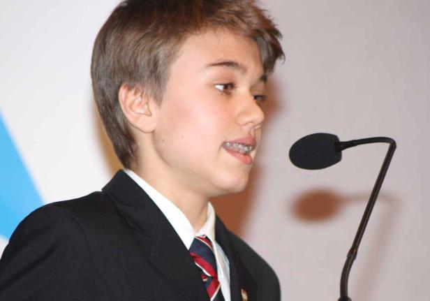 Ein junger Mann mit Zahnspange spricht in ein Mikrofon.