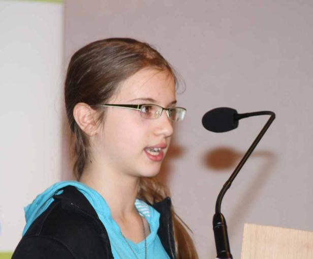 Ein junges Mädchen spricht am Rednerpult in ein Mikrofon.