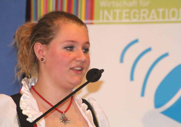 Eine junge Frau im Dirndl spricht in ein Mikrofon.