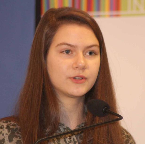 Eine junge Frau spricht vor einem Mikrofon.