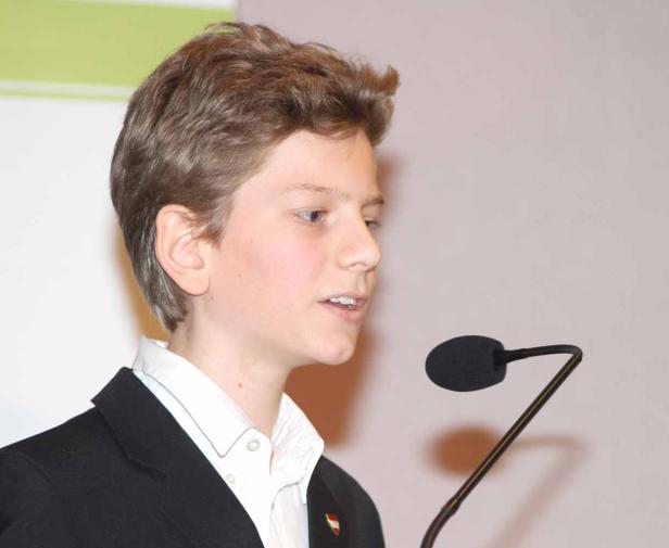 Ein junger Mann in einem Anzug spricht in ein Mikrofon.