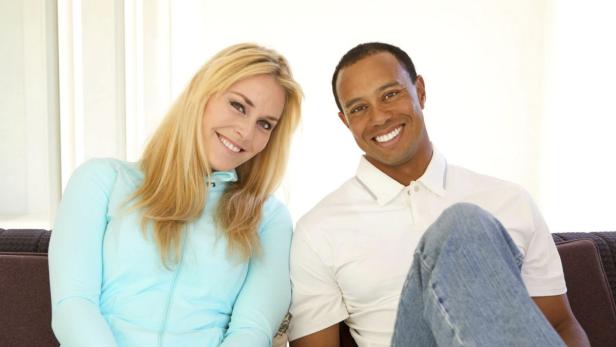 Lindsey Vonn und Tiger Woods sitzen lächelnd auf einem Sofa.