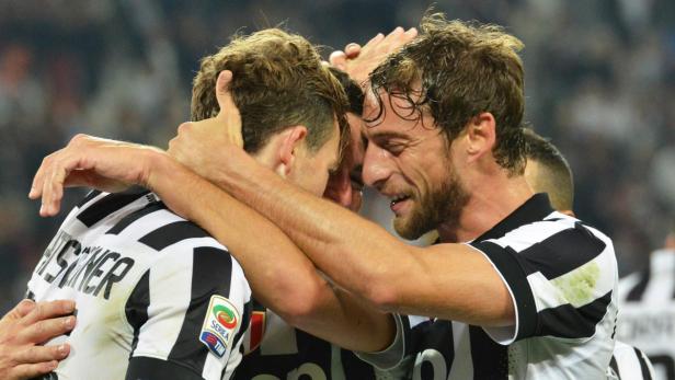 Jubelnde Fußballspieler von Juventus Turin umarmen sich.