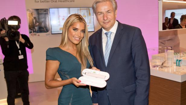 Eine Frau und ein Mann präsentieren eine elektrische Zahnbürste in einem Etui.