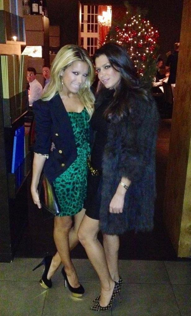 Zwei Frauen posieren in einem eleganten Restaurant mit Weihnachtsbaum.