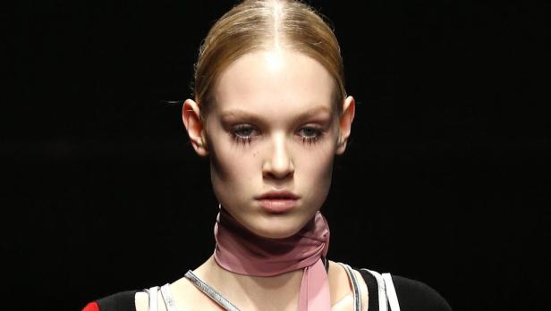 Ein Model mit blasser Haut und auffälligem Make-up präsentiert einen Look.