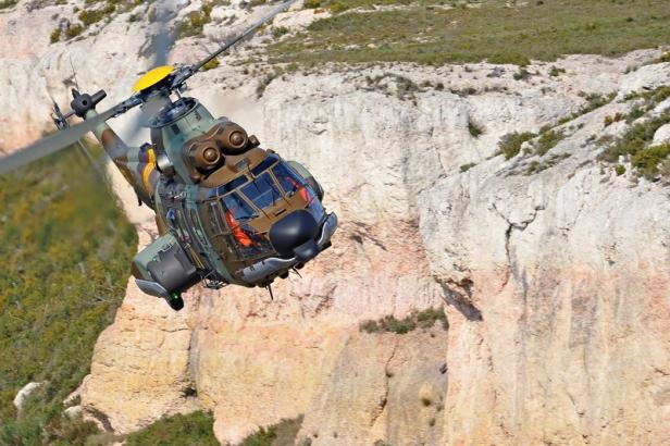 Ein Militärhubschrauber fliegt vor einer felsigen Landschaft.