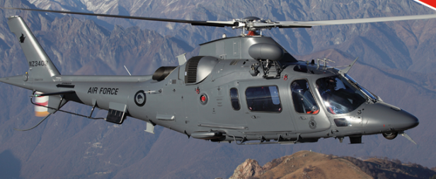 Ein grauer Militärhubschrauber der Luftwaffe fliegt vor einer Bergkulisse.