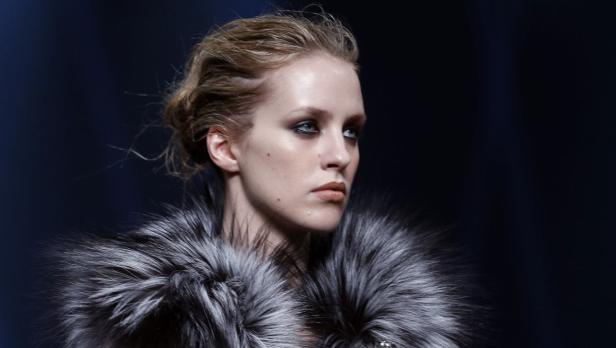 Eine Frau mit dunklem Make-up und einem Pelzkragen blickt zur Seite.
