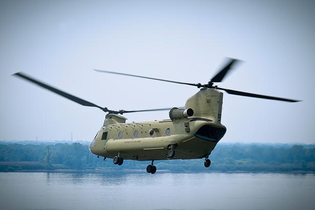 Ein Chinook-Militärhubschrauber der US-Armee fliegt über ein Gewässer.