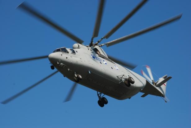 Ein grauer Militärhubschrauber fliegt vor blauem Himmel.