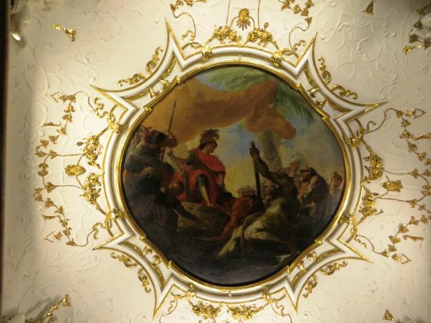 Deckengemälde mit einer Szene, die eine Gruppe von Menschen um eine zentrale Figur zeigt.