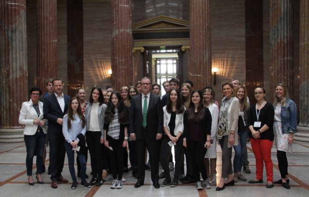 Eine Gruppe von Menschen posiert in einem Gebäude mit Säulen für ein Foto.