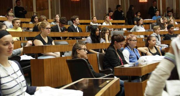 Eine Gruppe junger Menschen sitzt in einem Hörsaal oder Konferenzraum.