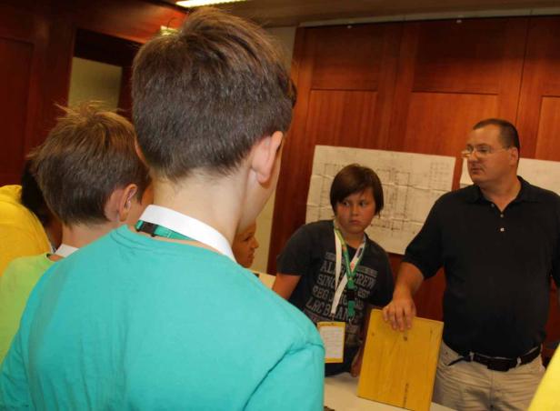 Eine Gruppe von Kindern und ein Mann stehen in einem Raum mit Holzvertäfelung.