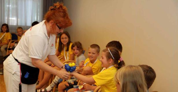 Eine Frau mit roten Haaren überreicht einem Mädchen einen Ballon.