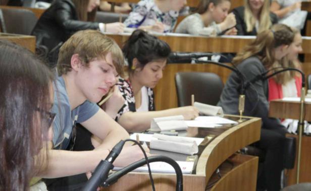 Mehrere Studenten sitzen in einem Hörsaal und machen sich Notizen.