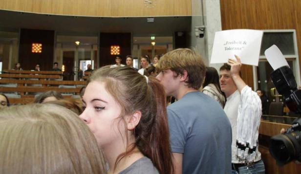 Menschen demonstrieren mit einem Schild, auf dem „Freiheit & Toleranz“ steht.