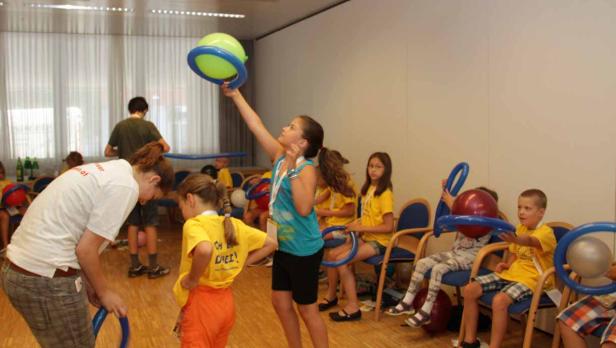 Kinder spielen mit Ballons in einem hellen Raum.
