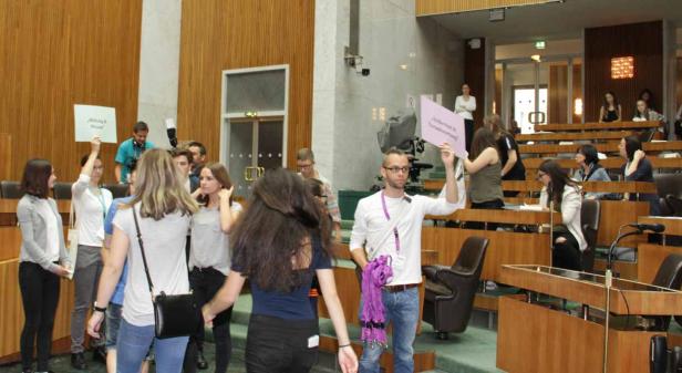 Eine Gruppe junger Leute demonstriert im Parlament mit Schildern.