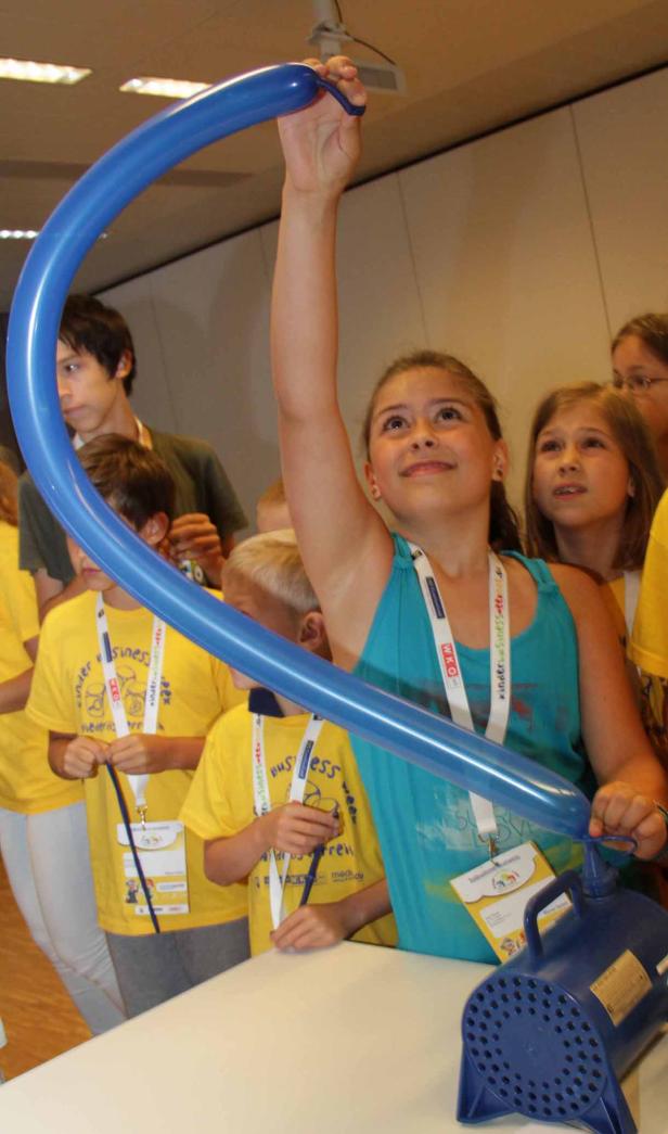 Ein Mädchen hält einen blauen, geformten Ballon hoch.