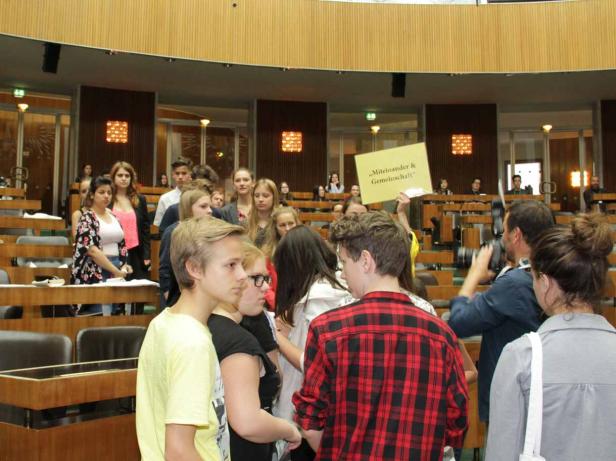 Eine Gruppe junger Menschen hält ein Schild mit der Aufschrift „Miteinander & Gemeinschaft“.