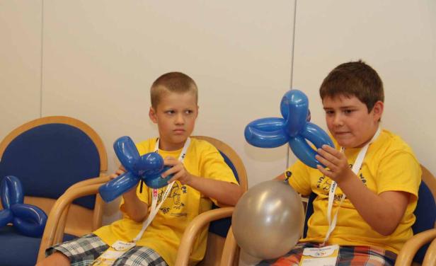 Zwei Jungen sitzen mit blauen und silbernen Luftballons da.