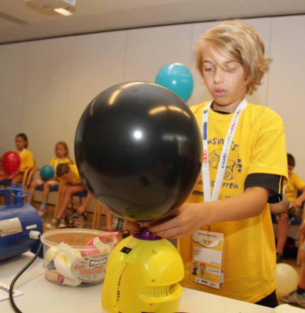 Ein Junge bläst einen schwarzen Ballon mit einer gelben Ballonpumpe auf.