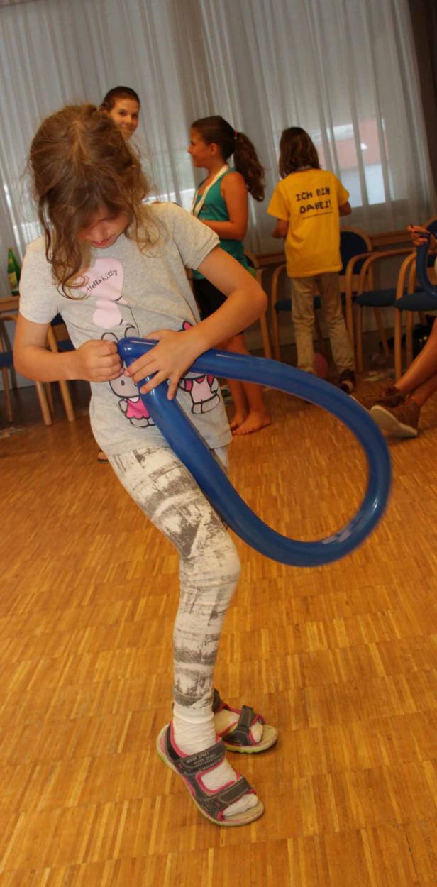 Ein Mädchen formt einen blauen Ballon zu einer Figur.