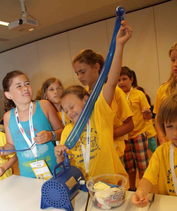 Eine Gruppe Kinder pumpt Luftballons mit einer elektrischen Pumpe auf.