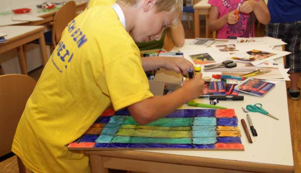 Ein Junge klebt ein farbiges Mosaik auf einem Tisch.