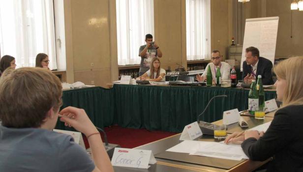 Personen sitzen an einem Tisch während einer Konferenz.