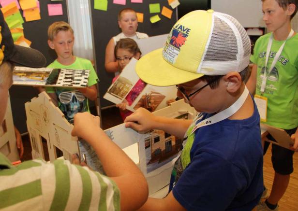 Eine Gruppe Kinder arbeitet an einem Architekturmodell.