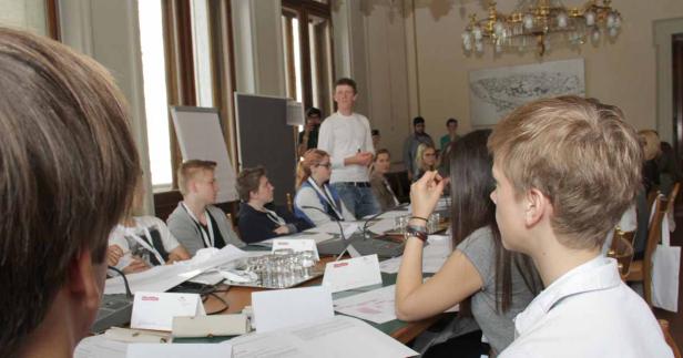 Ein junger Mann hält vor einer Gruppe von Zuhörern eine Präsentation.