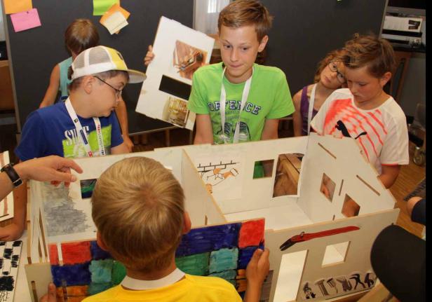 Eine Gruppe Kinder arbeitet an einem Modellhaus.