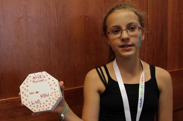 Ein Mädchen präsentiert eine Pralinenschachtel von Heindl's im Rahmen der Kinder Business Week.