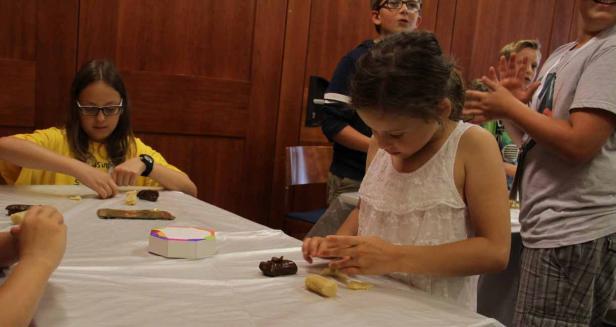 Kinder sitzen an einem Tisch und formen Figuren aus Teig.