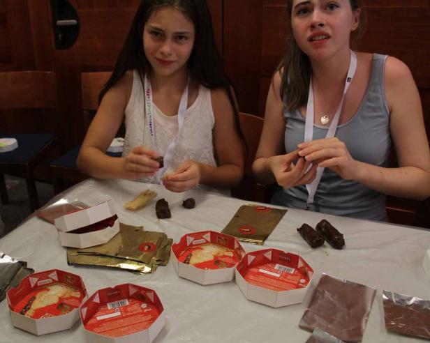 Zwei Mädchen sitzen an einem Tisch und verpacken Schokoladenprodukte der Marke Heindl.