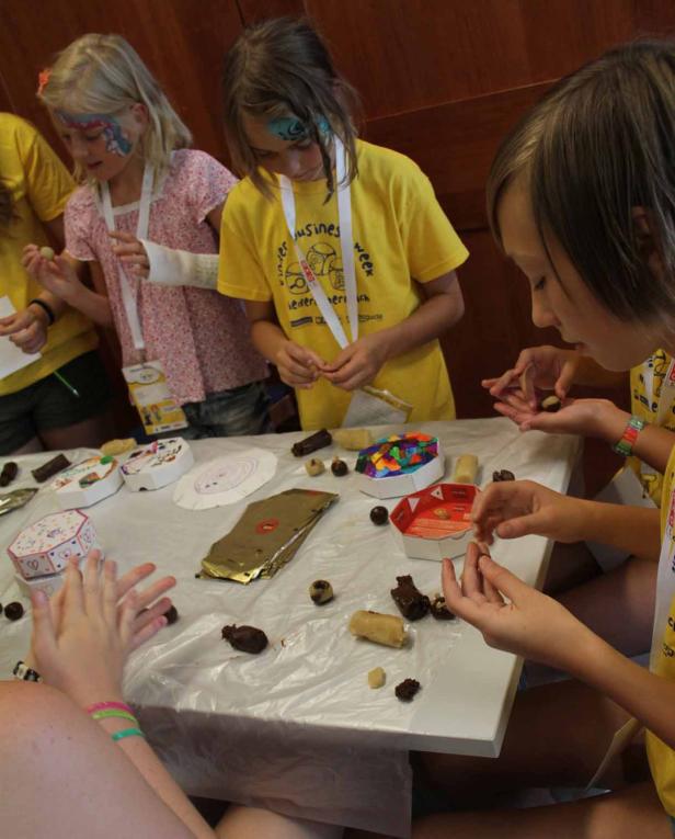 Mehrere Kinder sitzen an einem Tisch und formen Pralinen.