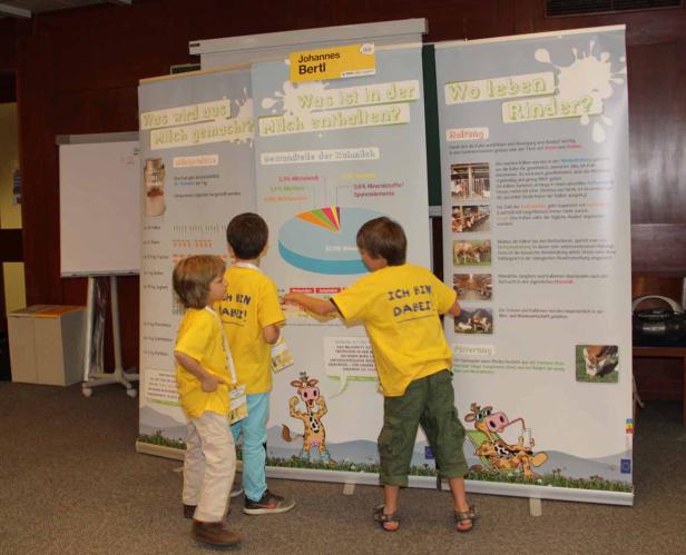 Drei Kinder betrachten einen Stand zum Thema Milchwirtschaft.