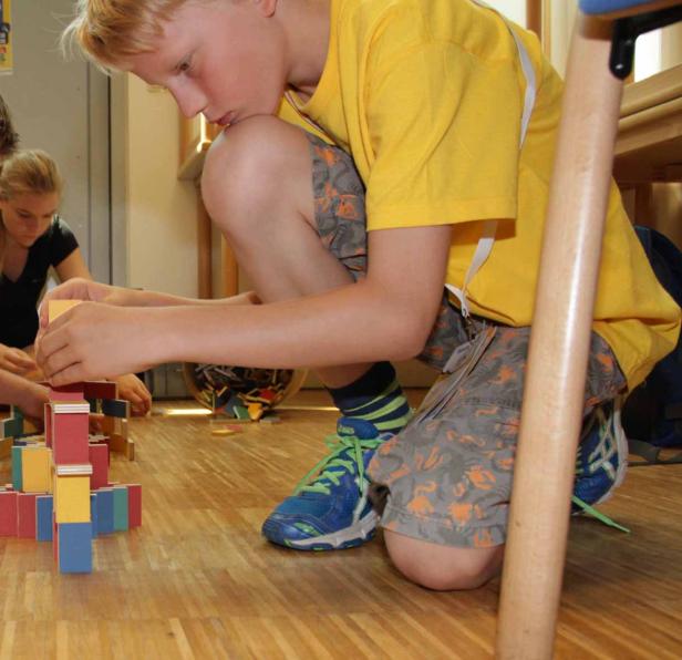 Ein Junge baut mit bunten Holzklötzen einen Turm.
