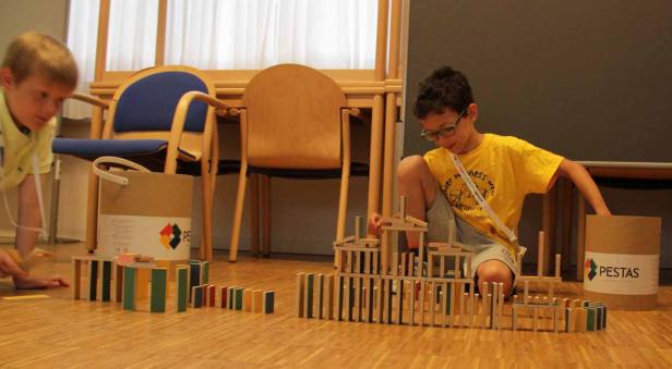 Zwei Kinder spielen mit Dominosteinen und bauen eine Konstruktion.