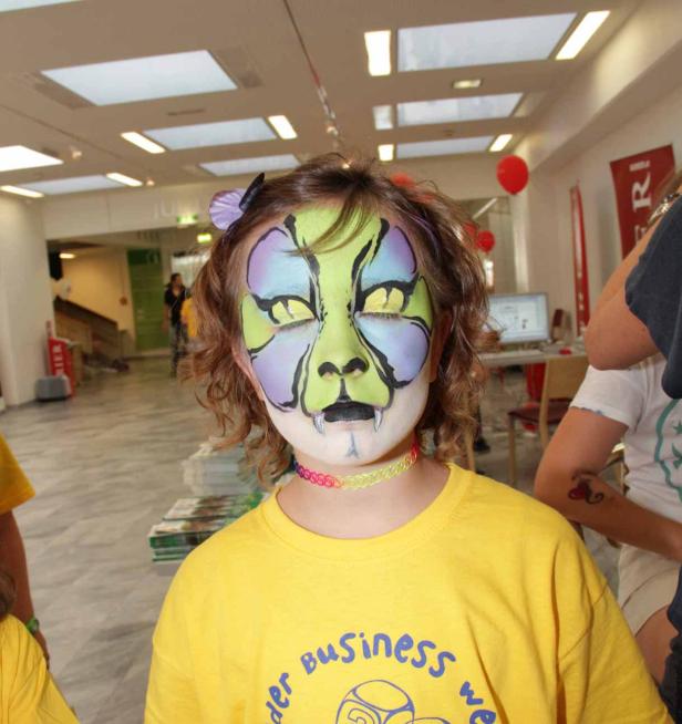 Ein Kind mit aufwendiger Gesichtsbemalung in einem Innenraum.