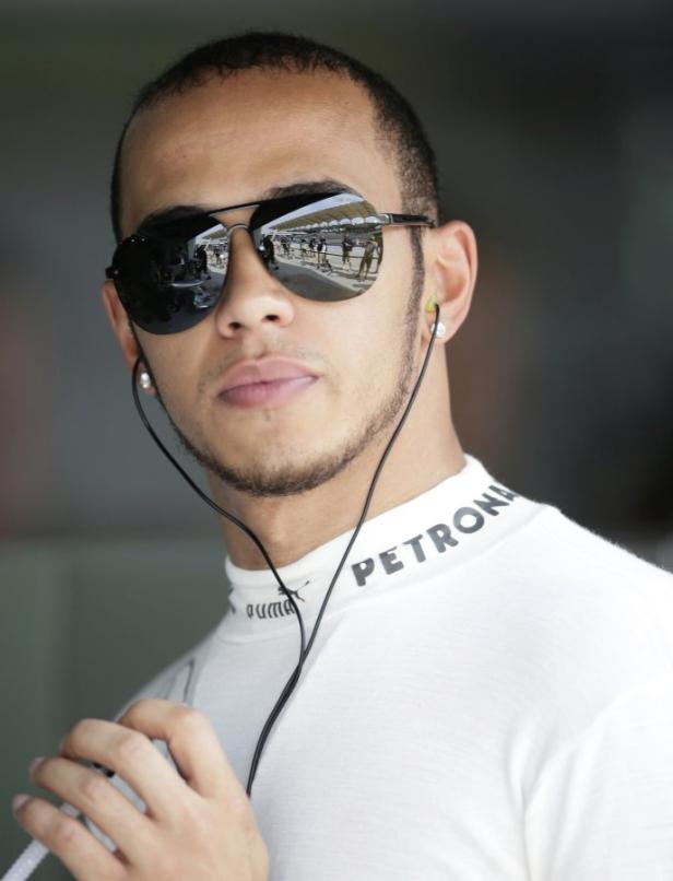 Lewis Hamilton mit Sonnenbrille und Kopfhörern im Fahrerlager.