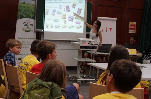 Eine Frau präsentiert Sojaprodukte vor einer Gruppe von Kindern.