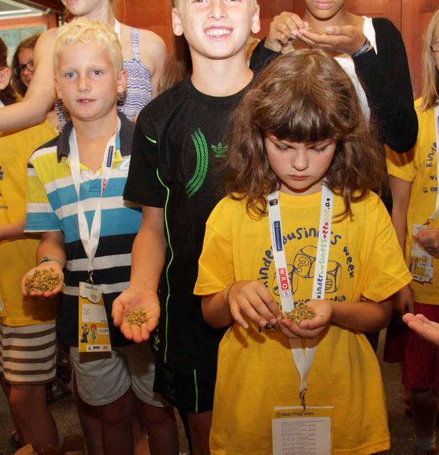 Eine Gruppe Kinder hält Getreidekörner in ihren Händen.