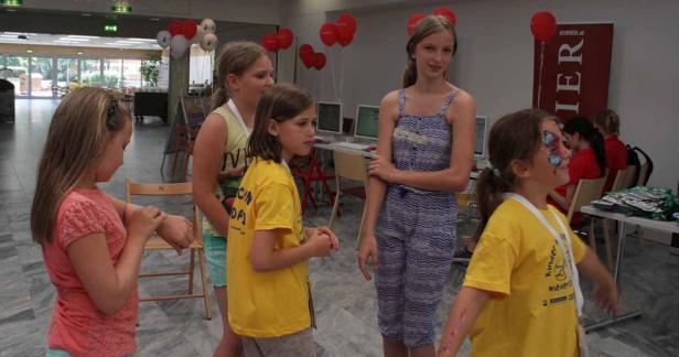 Eine Gruppe junger Mädchen steht in einem Raum mit roten und weißen Luftballons.