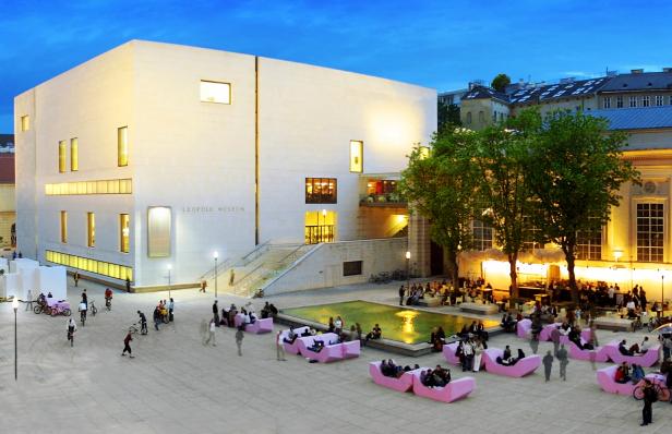 Das Leopold Museum in Wien mit Menschen auf pinkfarbenen Sofas vor dem Gebäude.