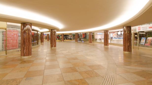 Eine leere Ladenpassage mit Säulen und Geschäften.